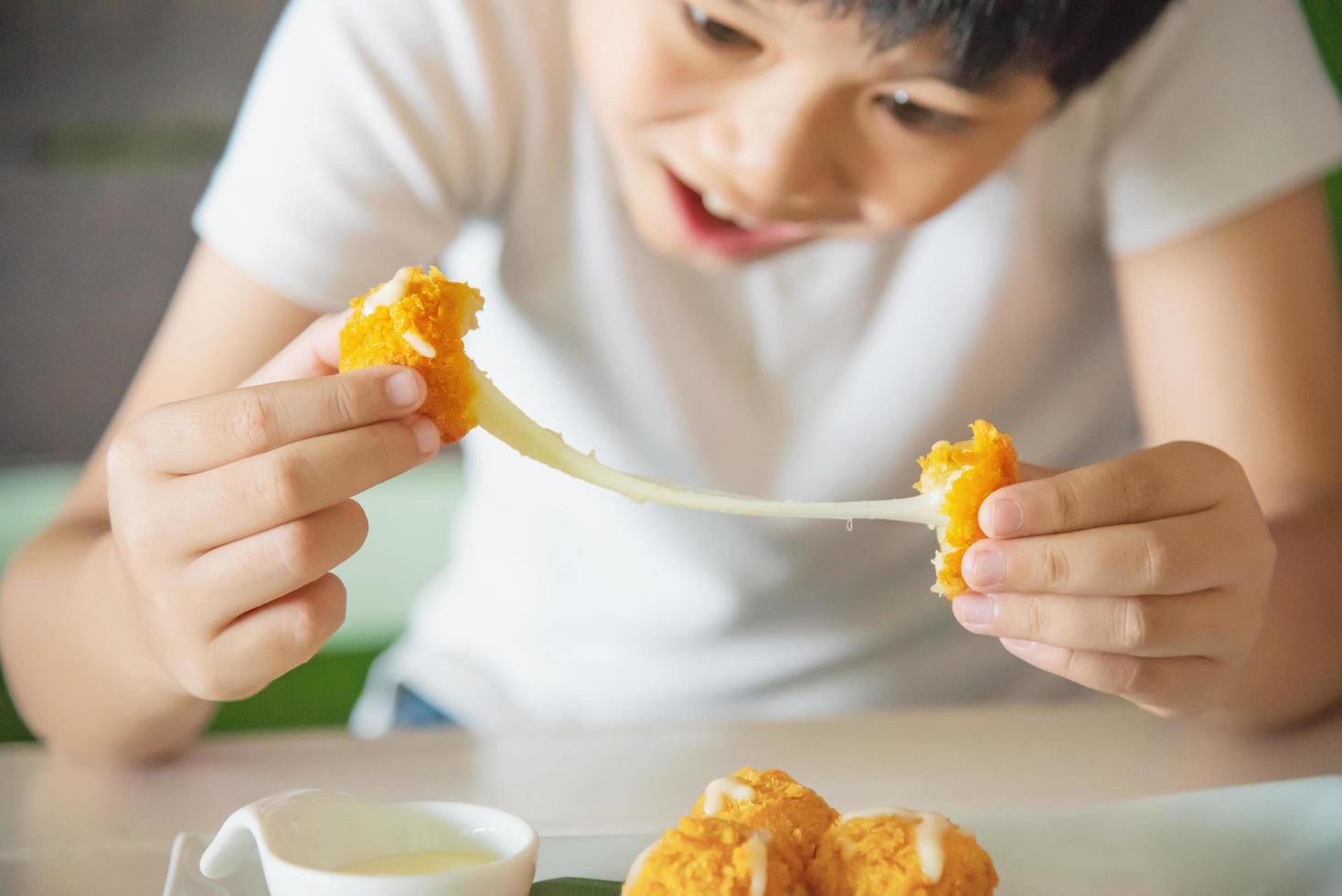 Boy ready to eat sticky stretch fried cheese ball - people and delicious cheese food concept photo