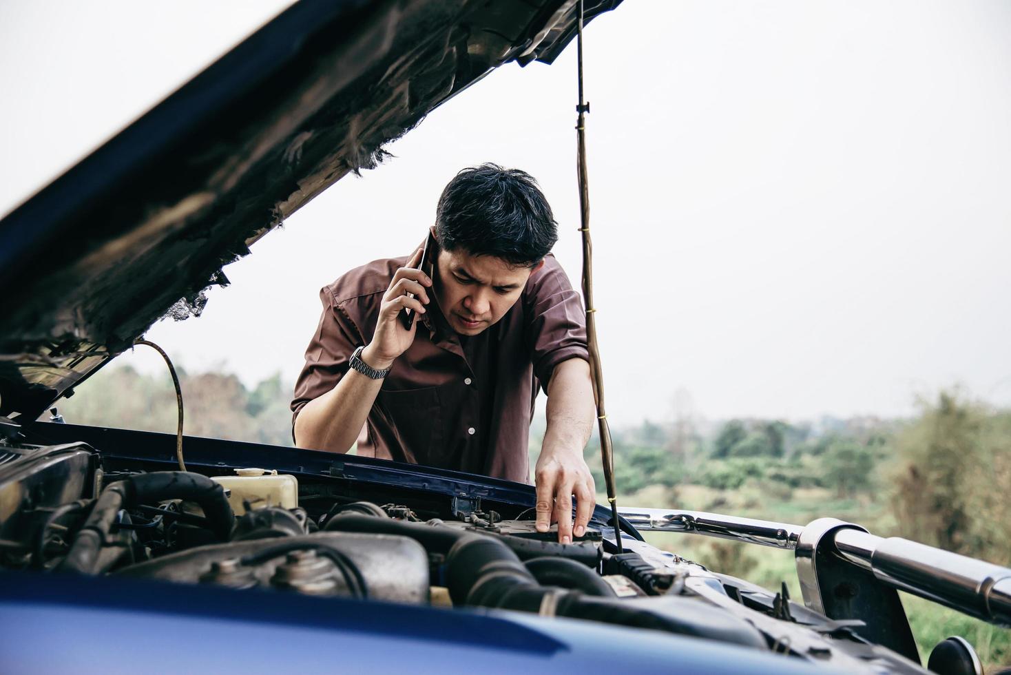 Man try to fix a car engine problem on a local road Chiang mai Thailand - people with car problem transportation concept photo