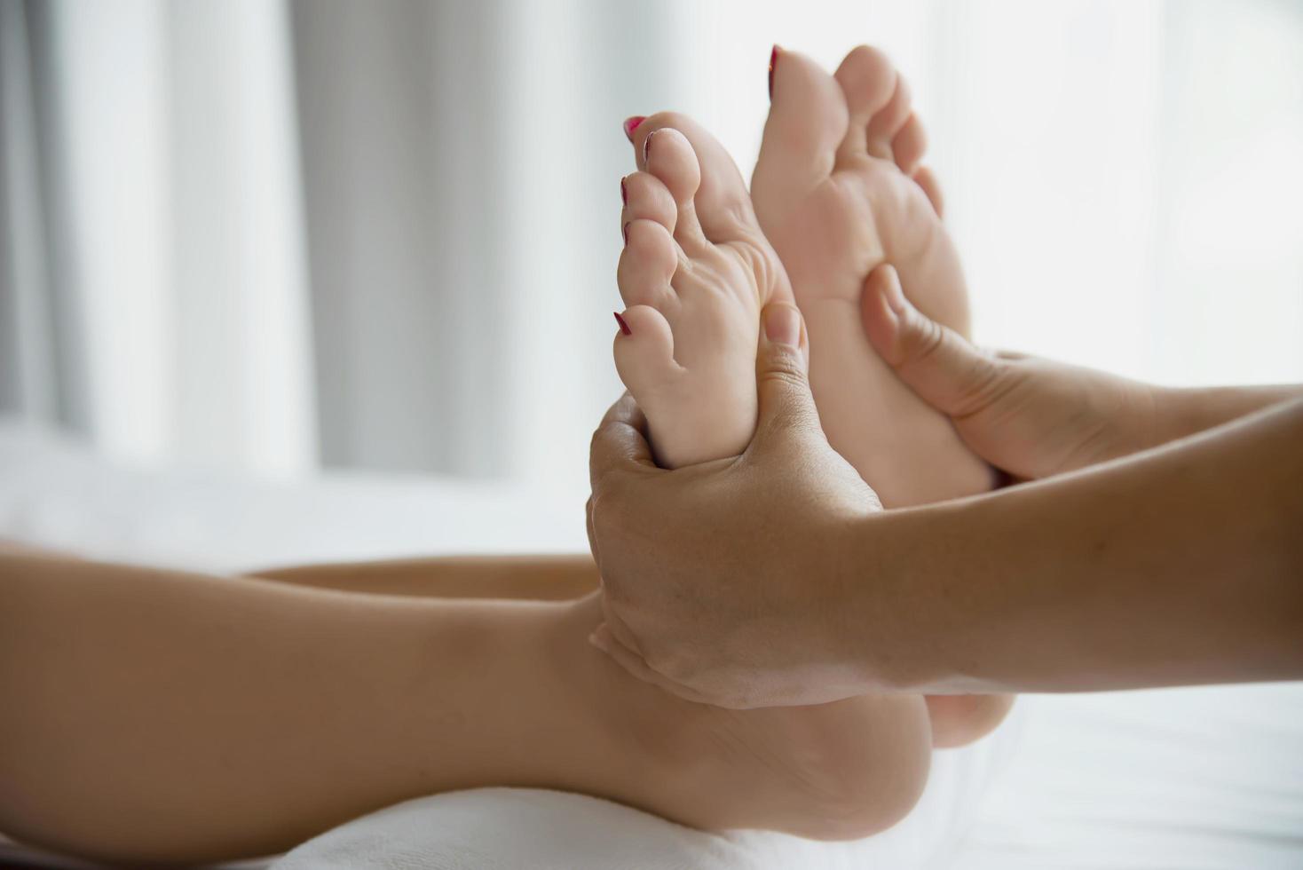 Woman receiving foot massage service from masseuse close up at hand and foot - relax in foot massage therapy service concept photo