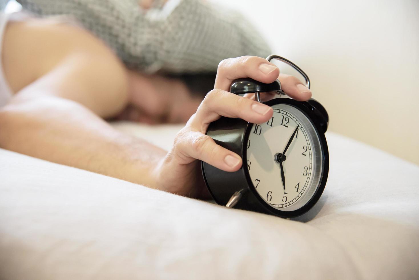 Sleepy man holding the alarm clock in the morning with late wake up - every day life at home concept photo