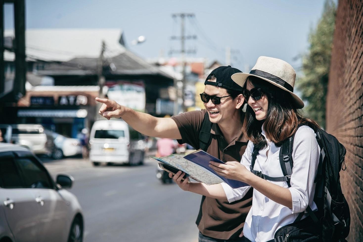 Asian backpack couple tourist holding city map crossing the road - travel people vacation lifestyle concept photo