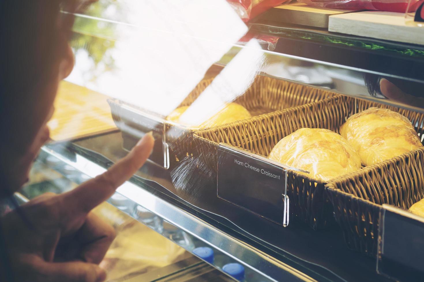 Lady is choosing bread in modern coffee bakery shop photo