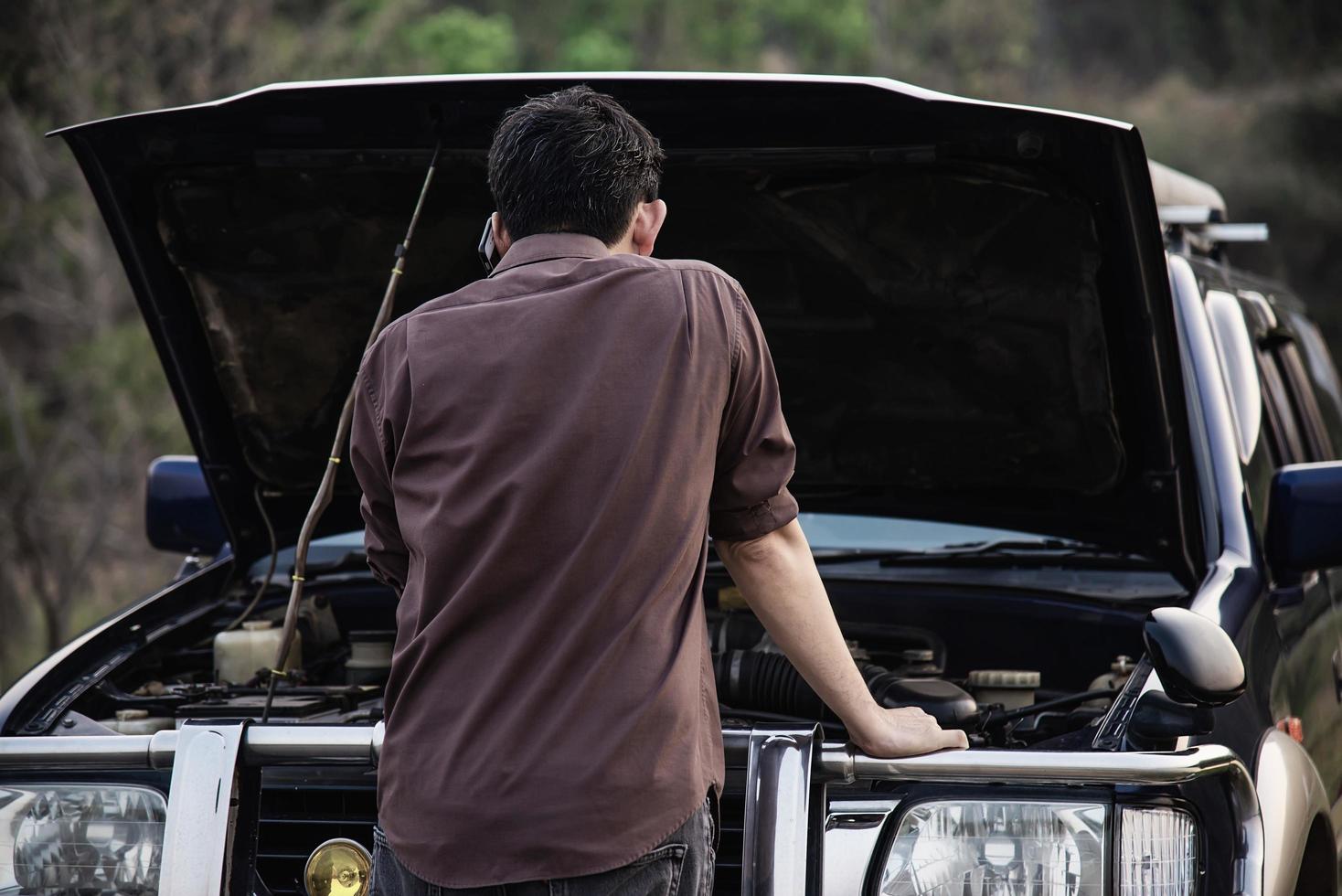 Man try to fix a car engine problem on a local road Chiang mai Thailand - people with car problem transportation concept photo