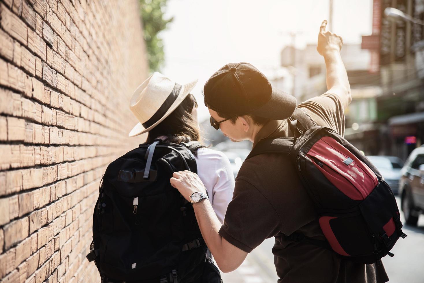 Asian backpack couple tourist holding city map crossing the road - travel people vacation lifestyle concept photo