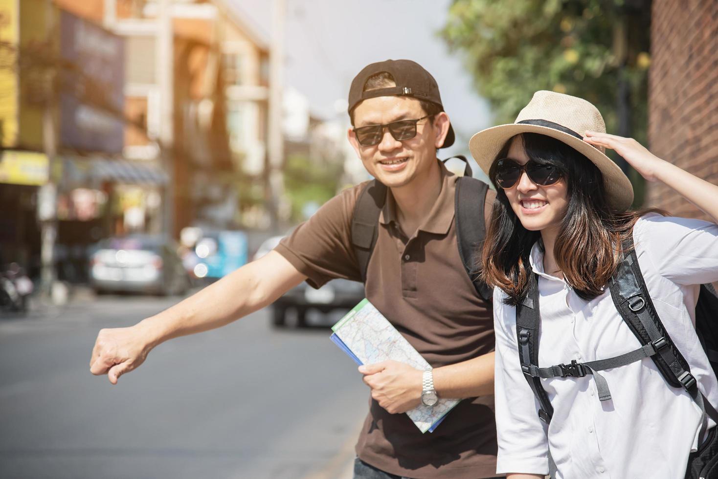 Asian backpack couple tourist holding city map crossing the road - travel people vacation lifestyle concept photo