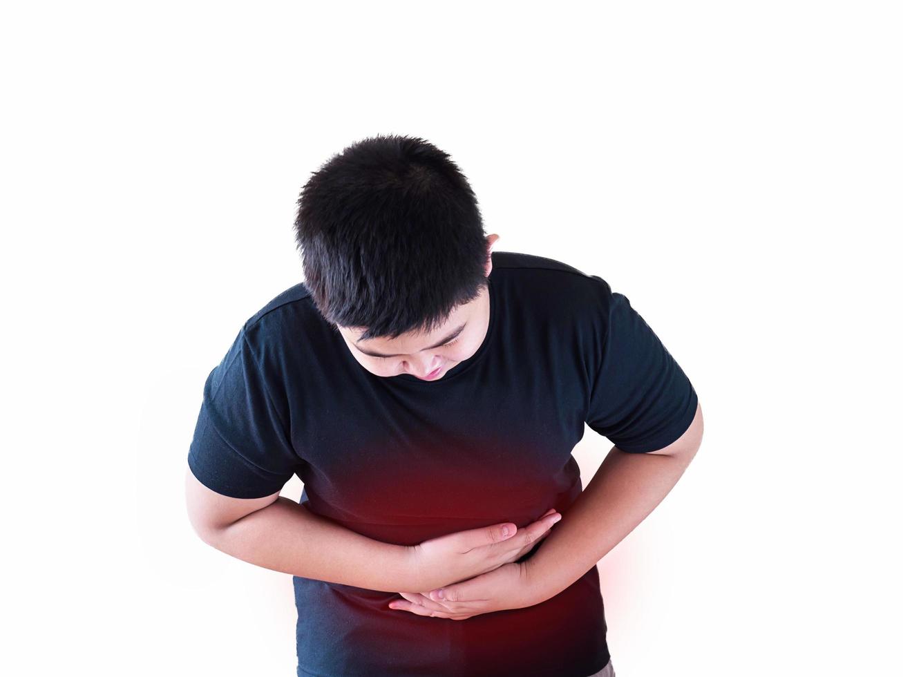 Boy having a stomachache holding his belly tightly with two hands with red pain coloring around his stomach photo