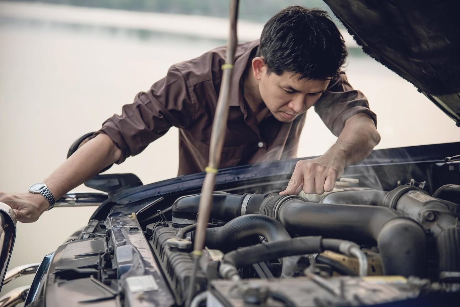 Man try to fix a car engine problem on a local road Chiang mai Thailand - people with car problem transportation concept photo