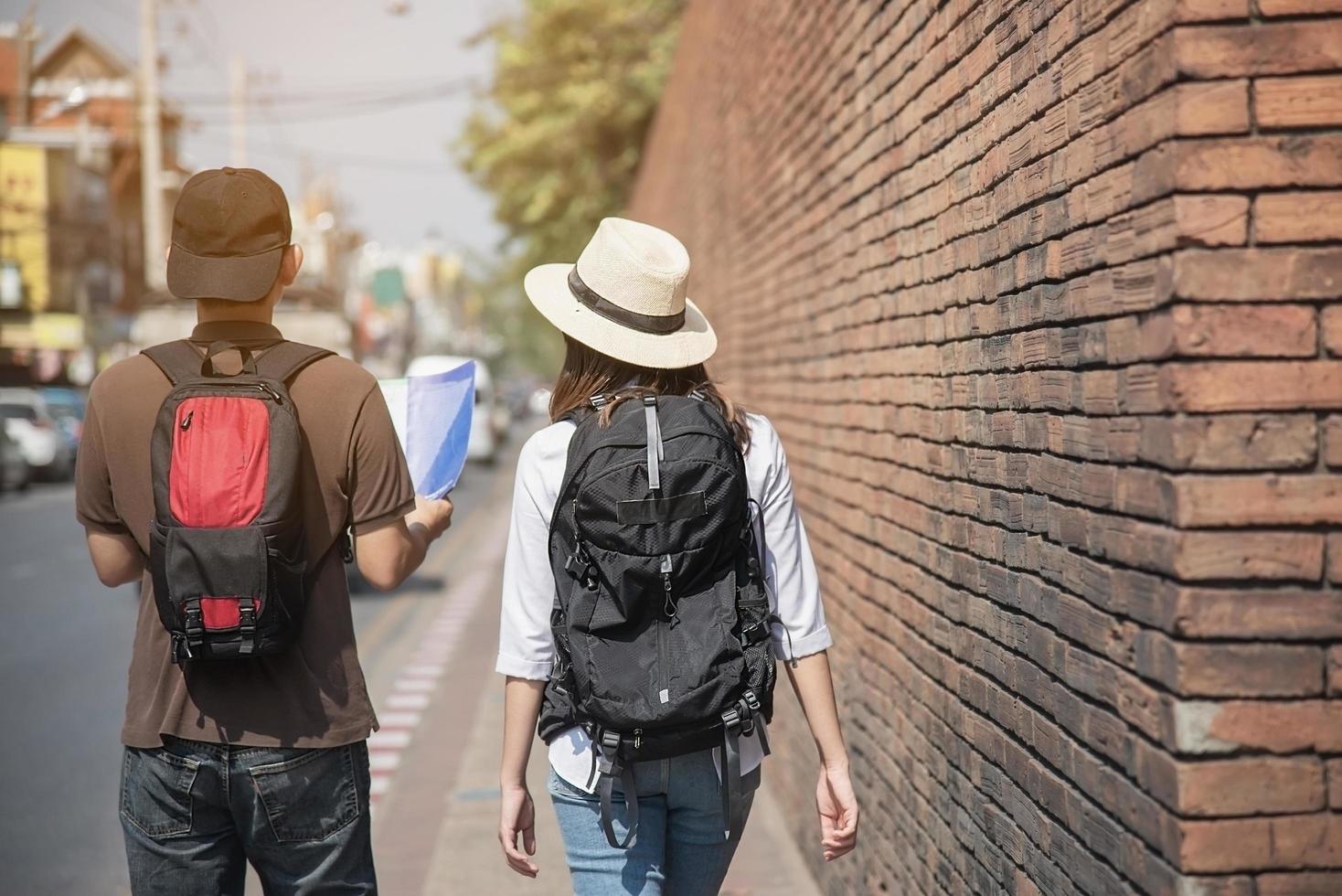 Asian backpack couple tourist holding city map crossing the road - travel people vacation lifestyle concept photo