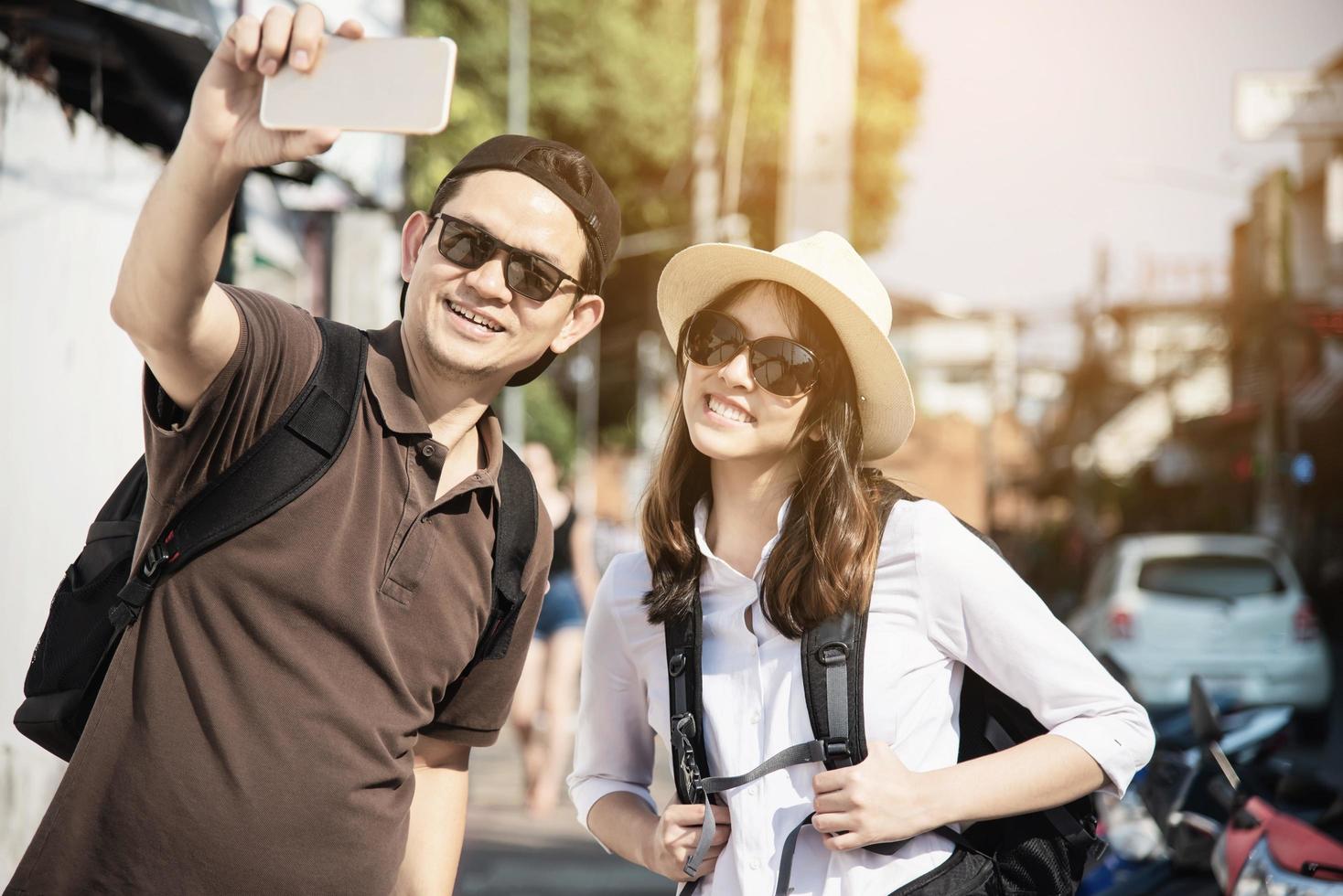 Asian backpack couple tourist holding city map crossing the road - travel people vacation lifestyle concept photo