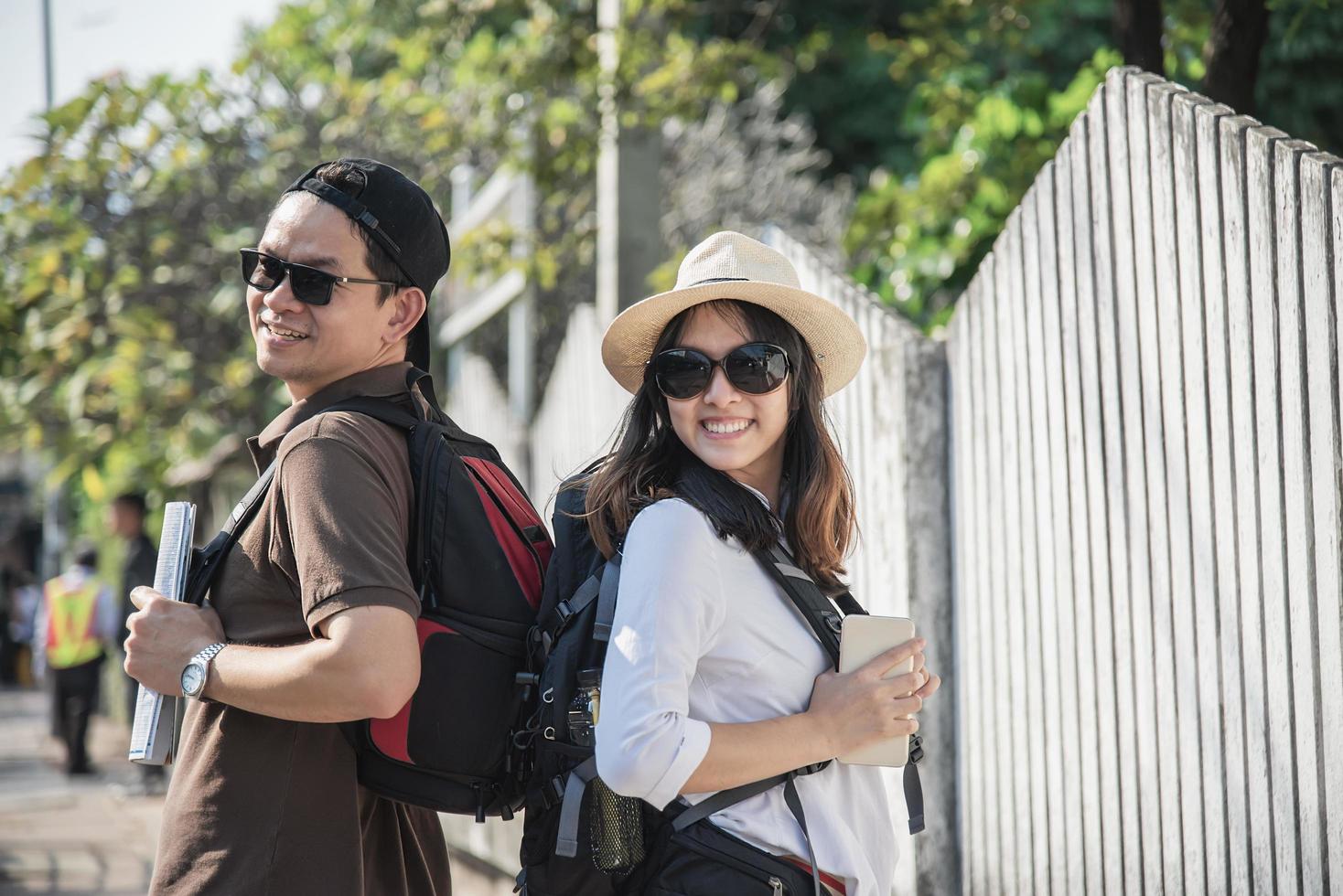 Asian backpack couple tourist holding city map crossing the road - travel people vacation lifestyle concept photo