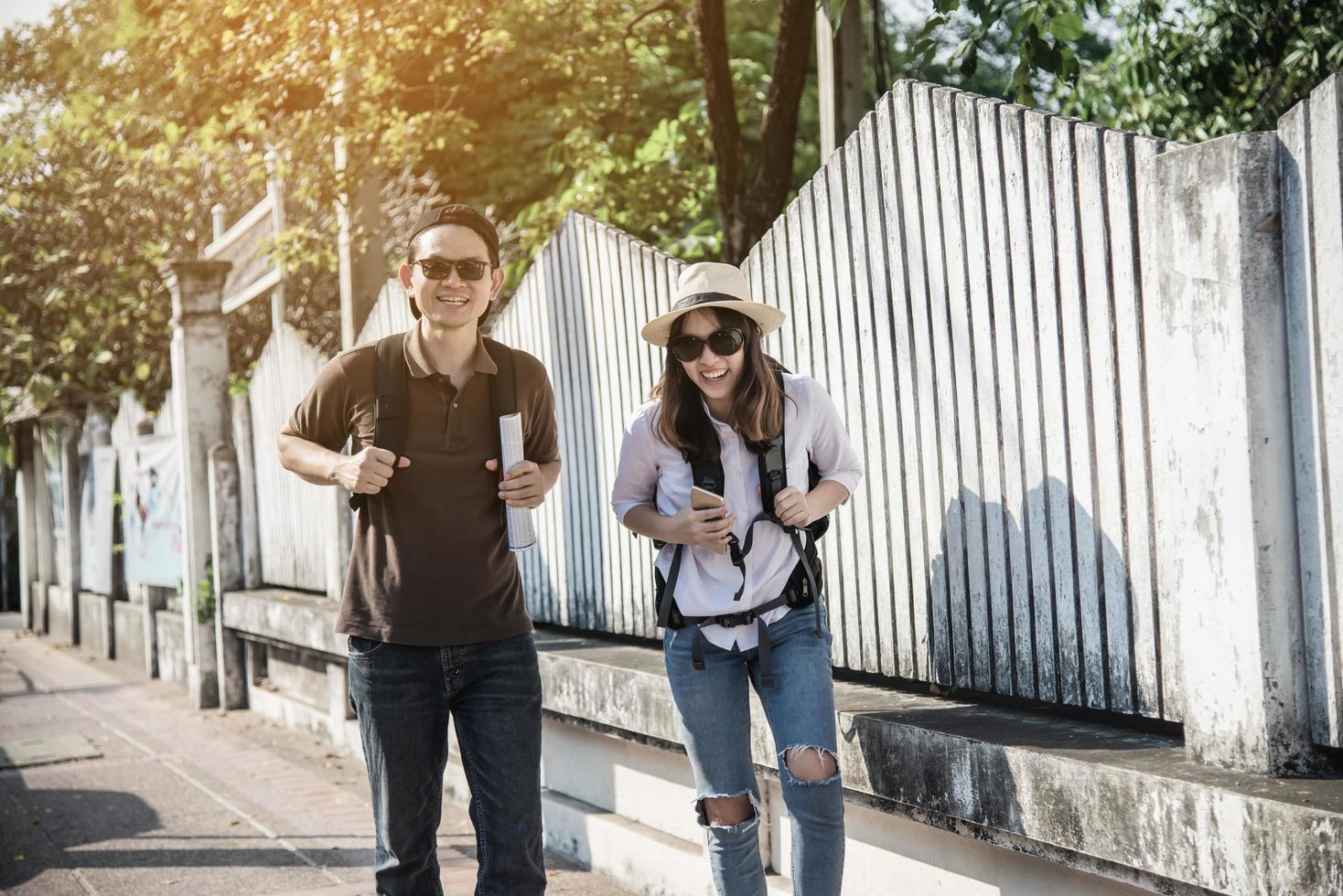 Asian backpack couple tourist holding city map crossing the road - travel people vacation lifestyle concept photo