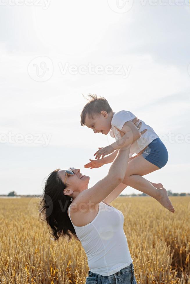 Happy family of mother and infant child walking on wheat field photo