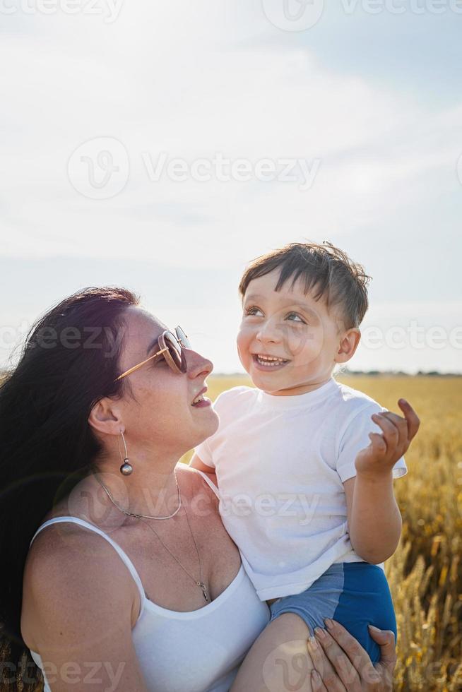 Happy family of mother and infant child walking on wheat field photo