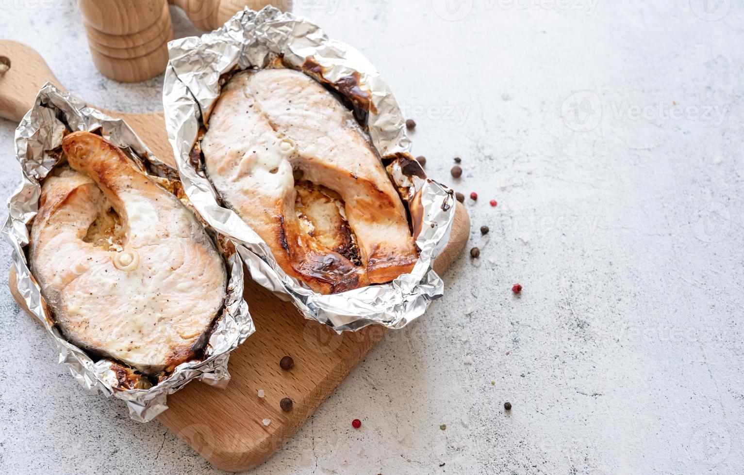 Grilled salmon steak on wooden cutting board on concrete background. Top view photo