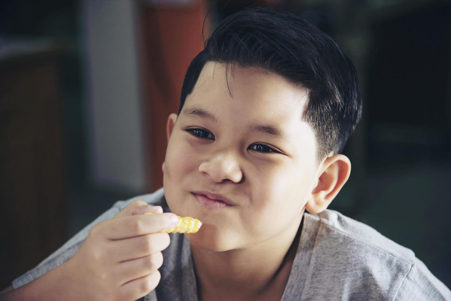 niño comiendo patatas fritas con salsa bañada en una mesa de madera blanca foto