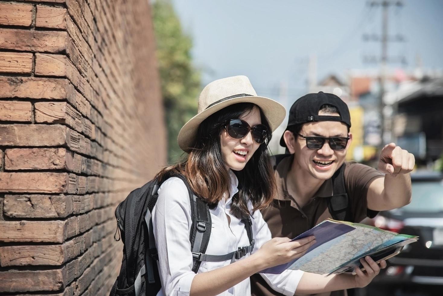 Asian backpack couple tourist holding city map crossing the road - travel people vacation lifestyle concept photo