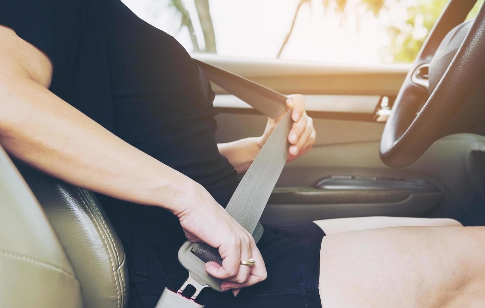 Lady putting car seat belt before driving, close up at belt buckle, safe drive concept photo