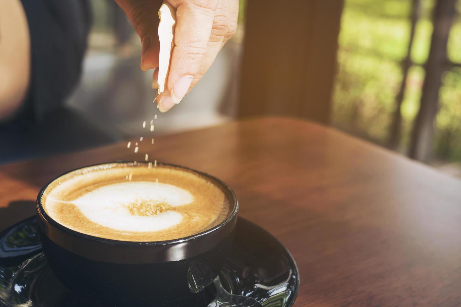 Closeup of lady pouring sugar while preparing hot coffee cup photo
