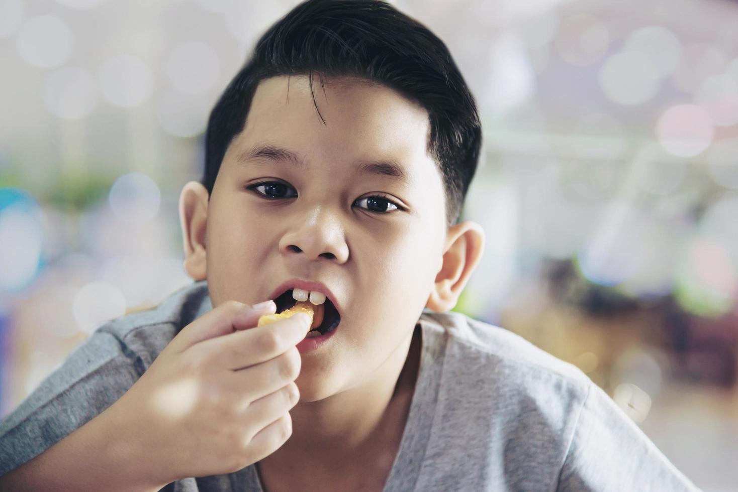 Boy eating French fries potato with dipped sauce over white wooden table photo