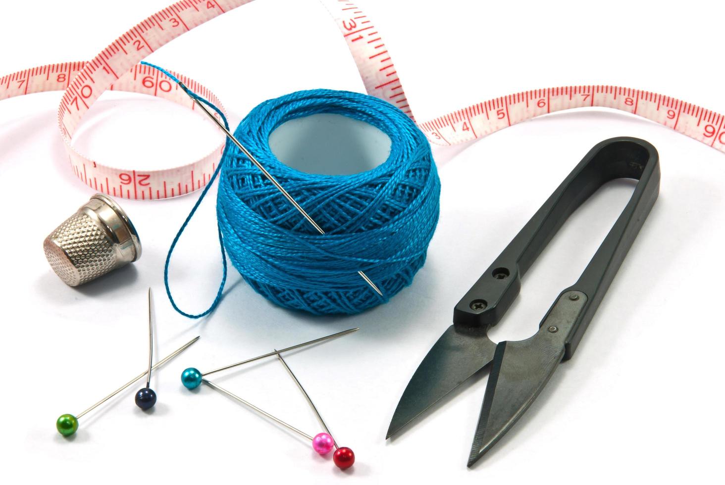 Thimble,needles and blue thread ball  for sewing on a background thread photo