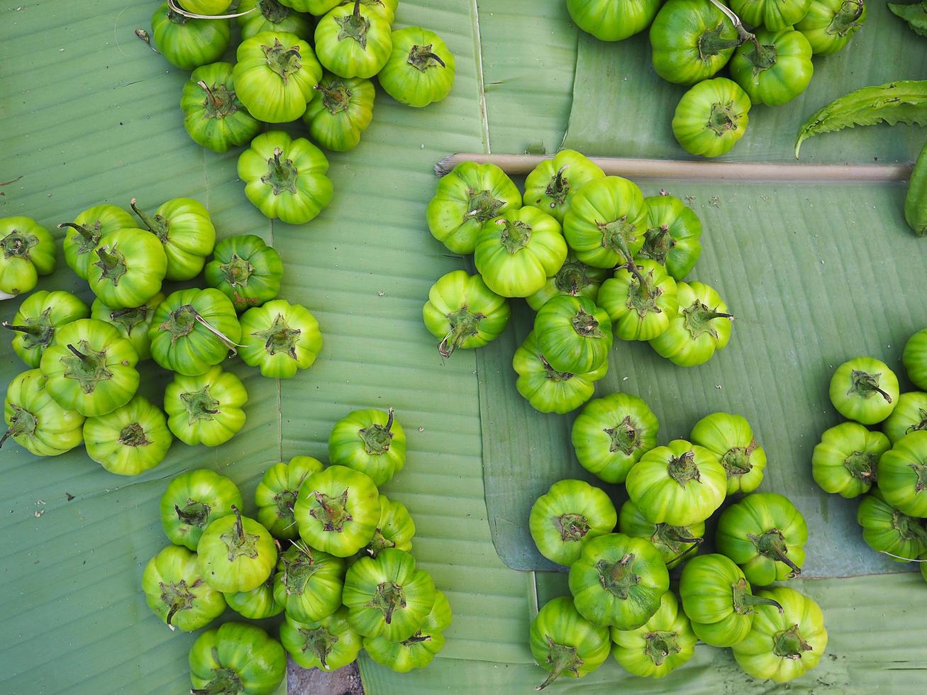 Pile of green eggplant on banana leaves for sale in market photo