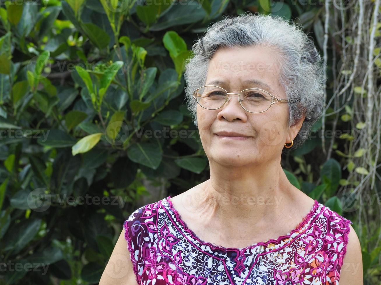 mujer mayor de pie sonriendo relajación en el jardín foto