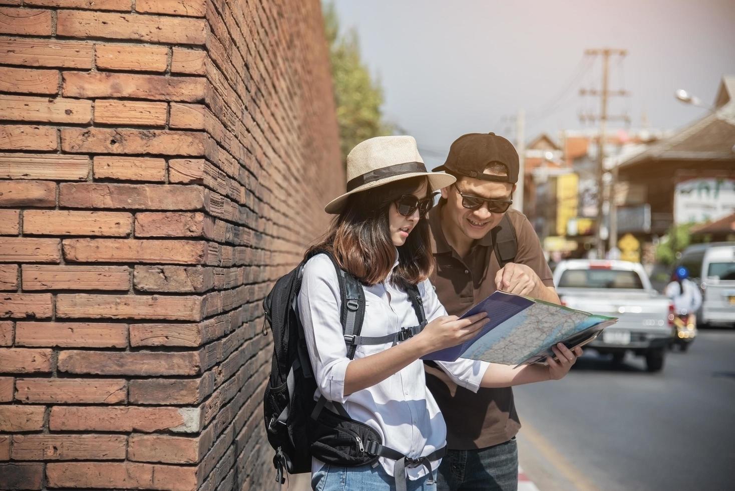 Asian backpack couple tourist holding city map crossing the road - travel people vacation lifestyle concept photo