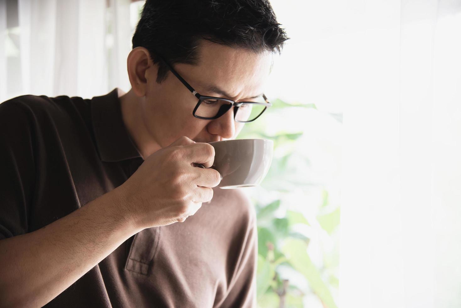 Relax Asian man drink coffee and read book in a modern style coffee shop - people with coffee cup easy lifestyle concept photo