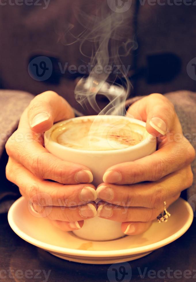 Woman hands hold a cup of coffee. Vertical image. Vintage style. photo