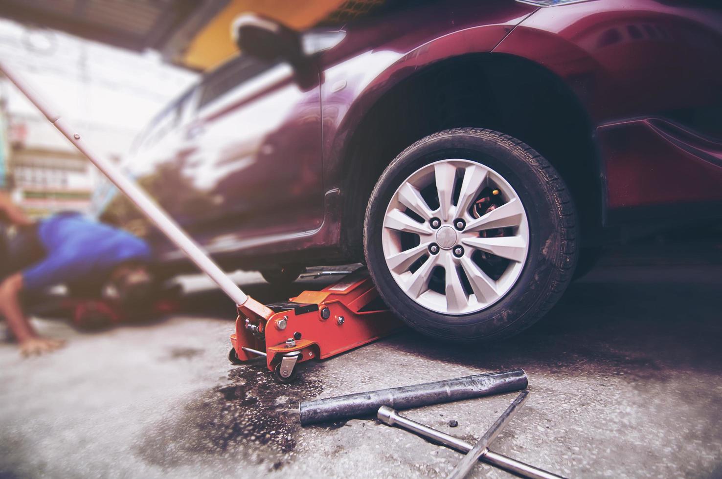 Car tire changed for maintenance in garage using hydraulic jack - car maintenance concept photo