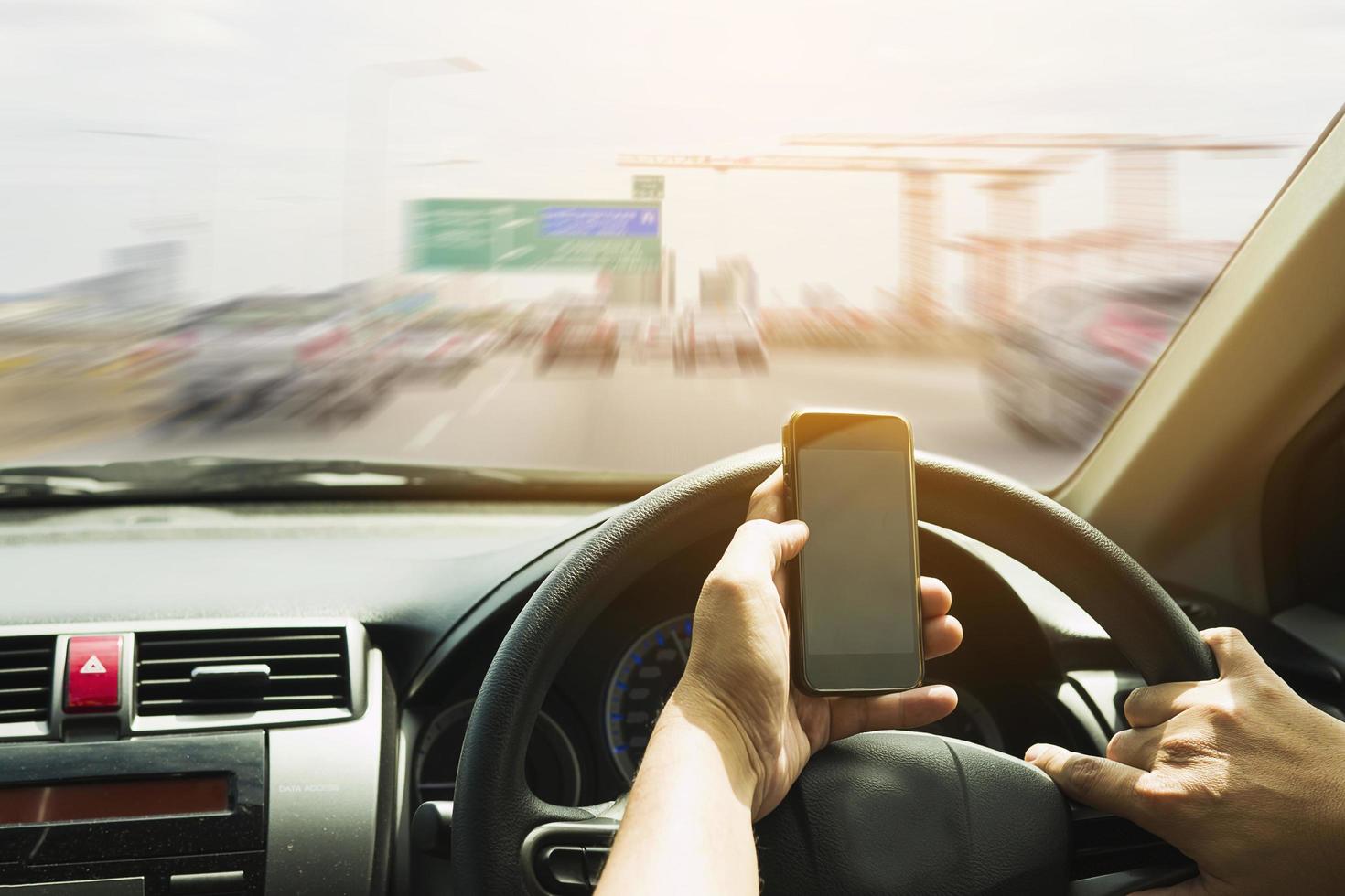 Close up of a man driving car dangerously while using mobile phone photo