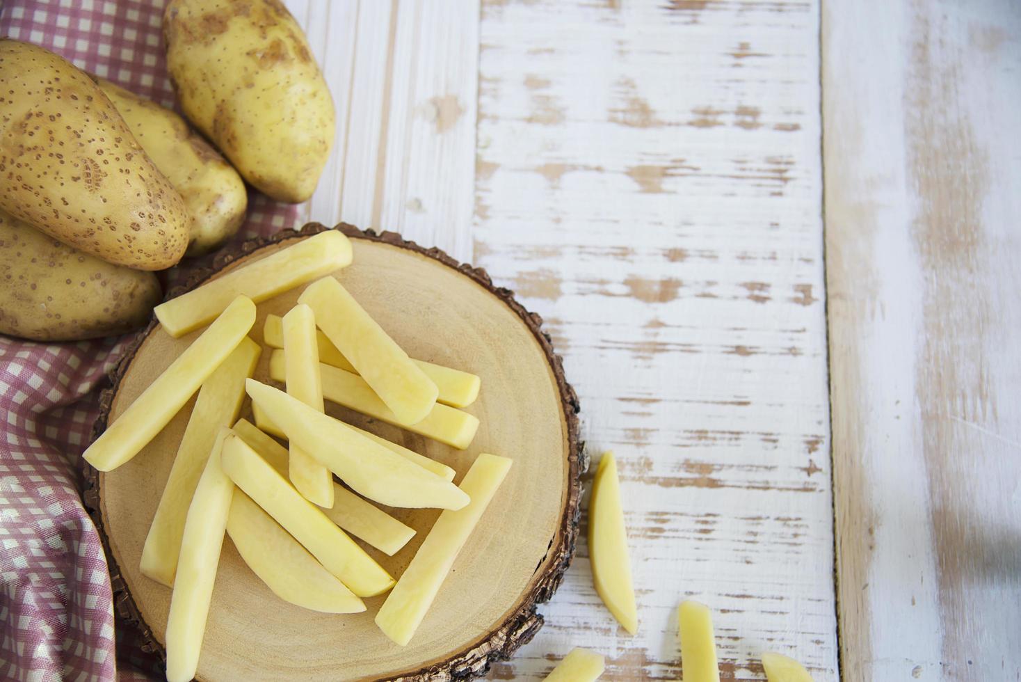palo de patata en rodajas listo para hacer patatas fritas - concepto tradicional de preparación de alimentos foto