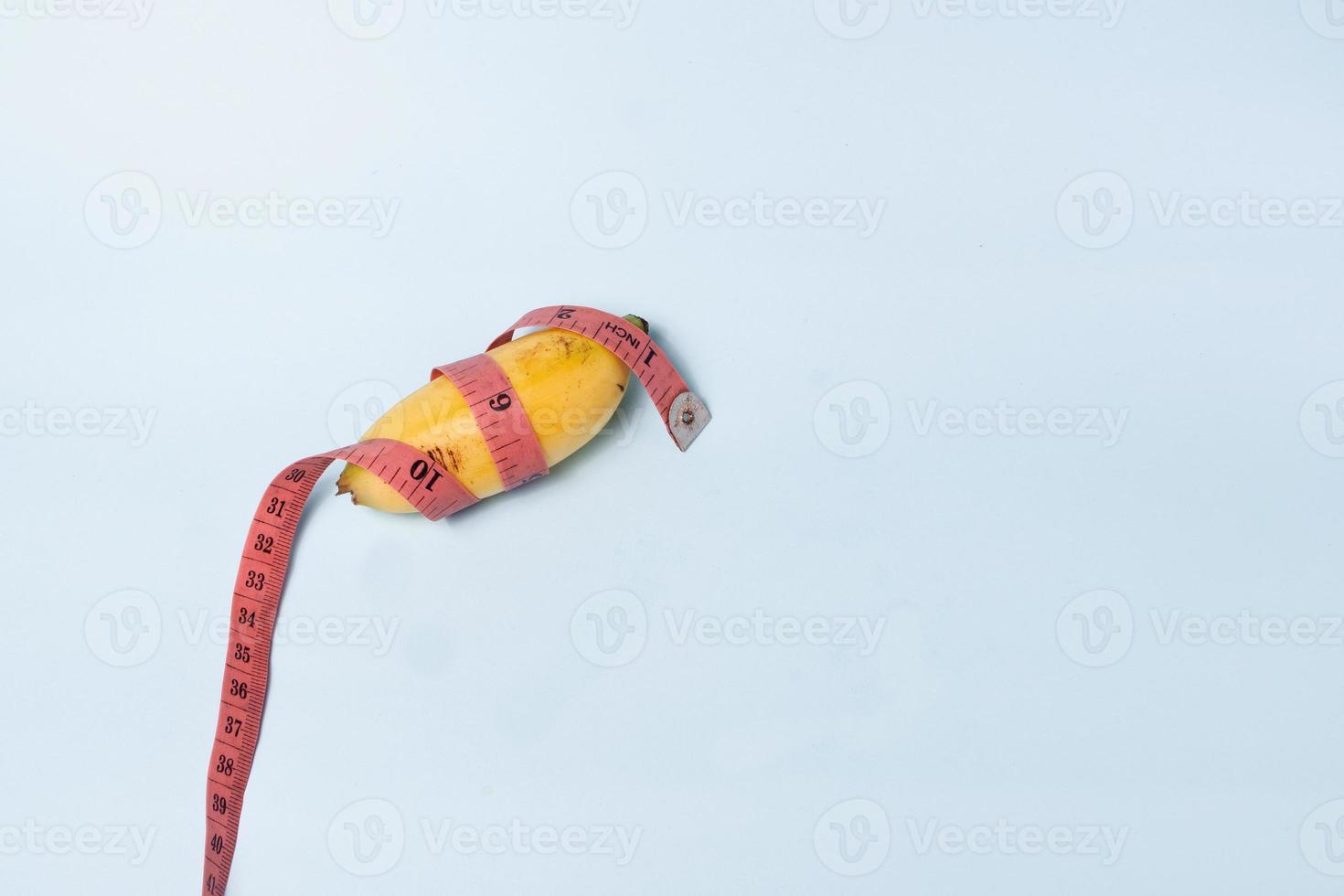 enfoque selectivo en la medición de un plátano pequeño usando una cinta métrica, concepto de tamaño de genitales masculinos pequeños foto