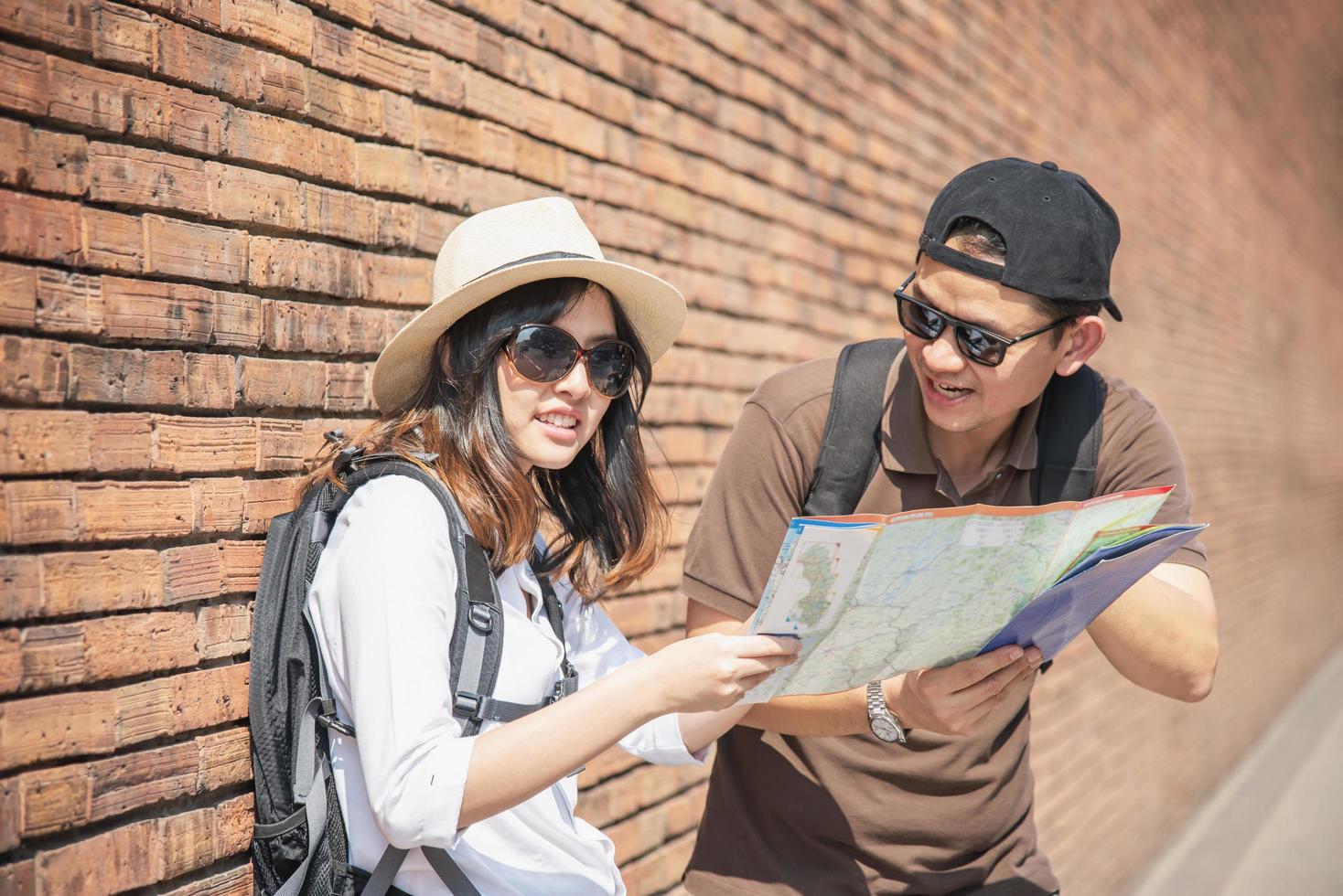 Asian backpack couple tourist holding city map crossing the road - travel people vacation lifestyle concept photo