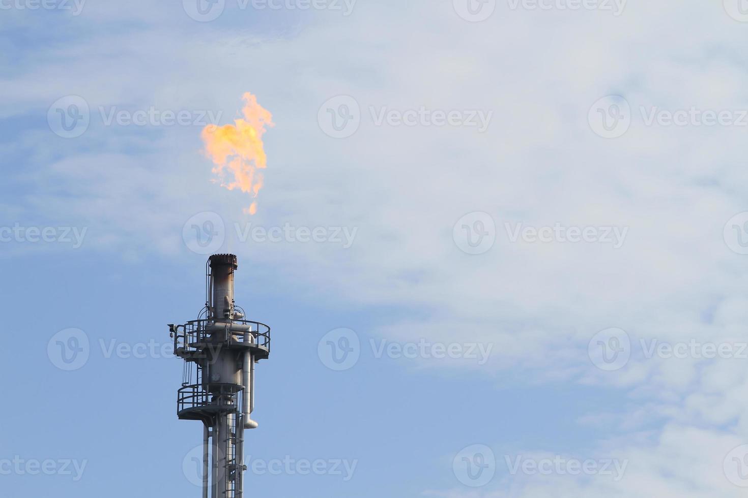 Burning oil flare on a blue sky photo
