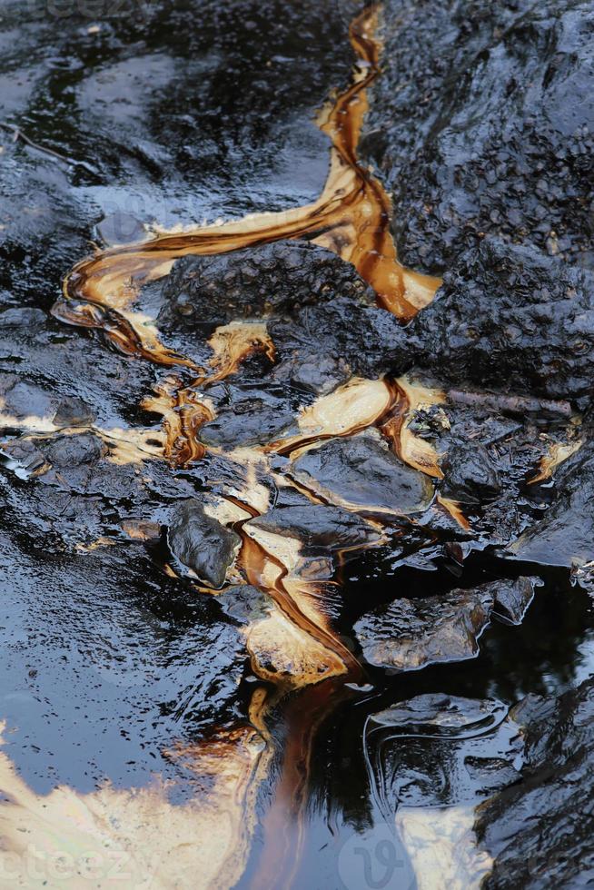 crude oil spill on the stone at the beach photo