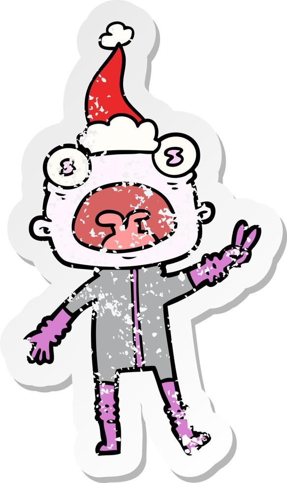 distressed sticker cartoon of a weird alien waving wearing santa hat vector