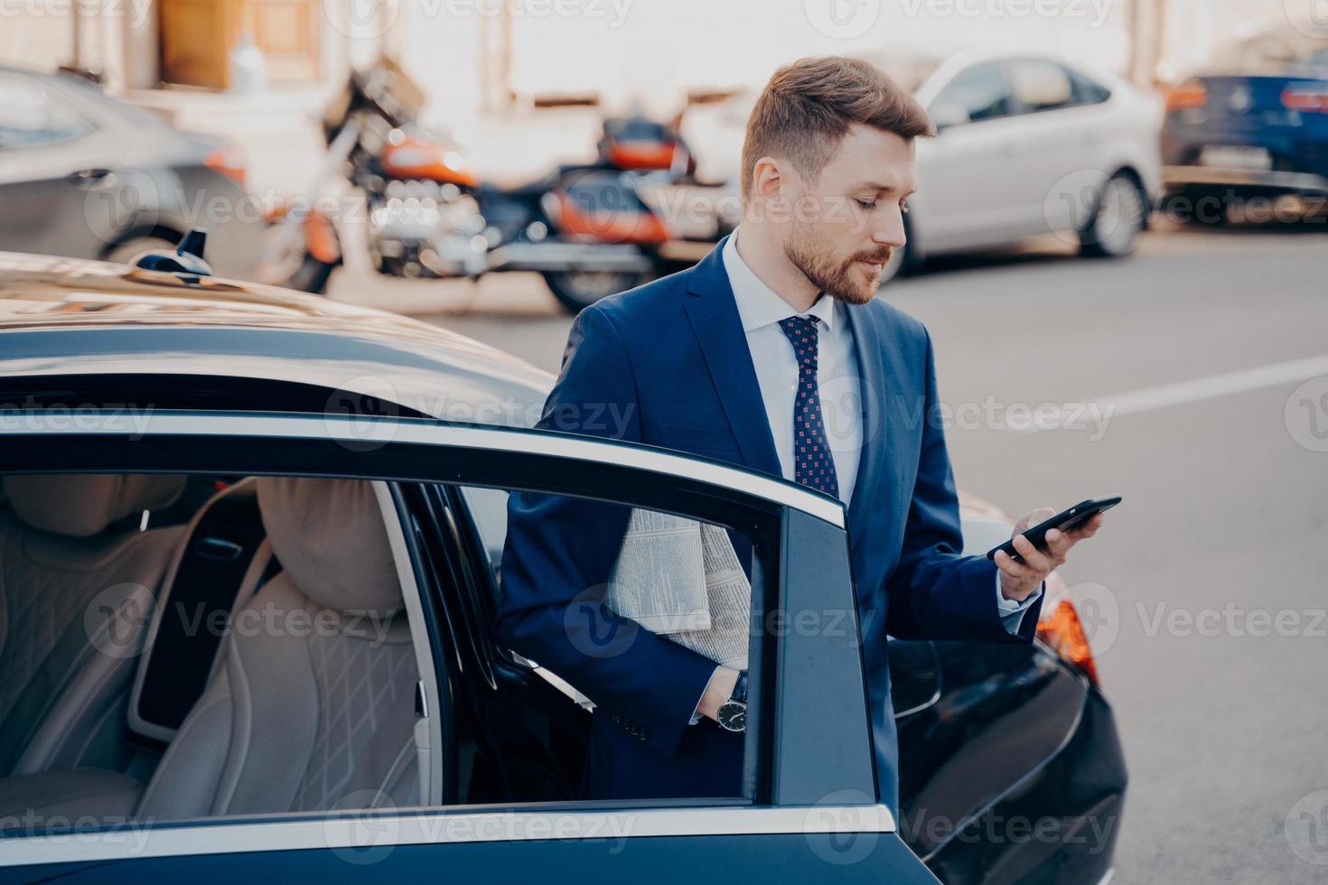 Successful executive manager in formal stylish tuxedo suit getting out of car photo