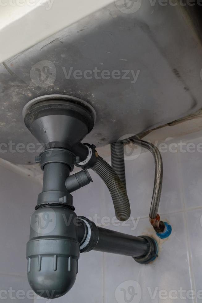 The drainage pipe system under the large sink in the house kitchen. photo
