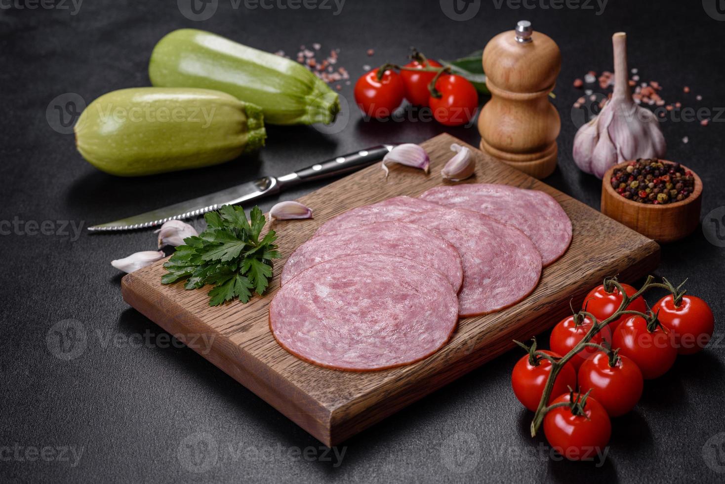 Slices of delicious fresh sausage on a wooden cutting board photo
