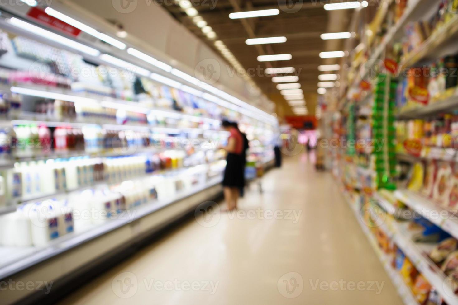 Pasillo de supermercado y estantes con productos lácteos en el fondo borroso del refrigerador foto