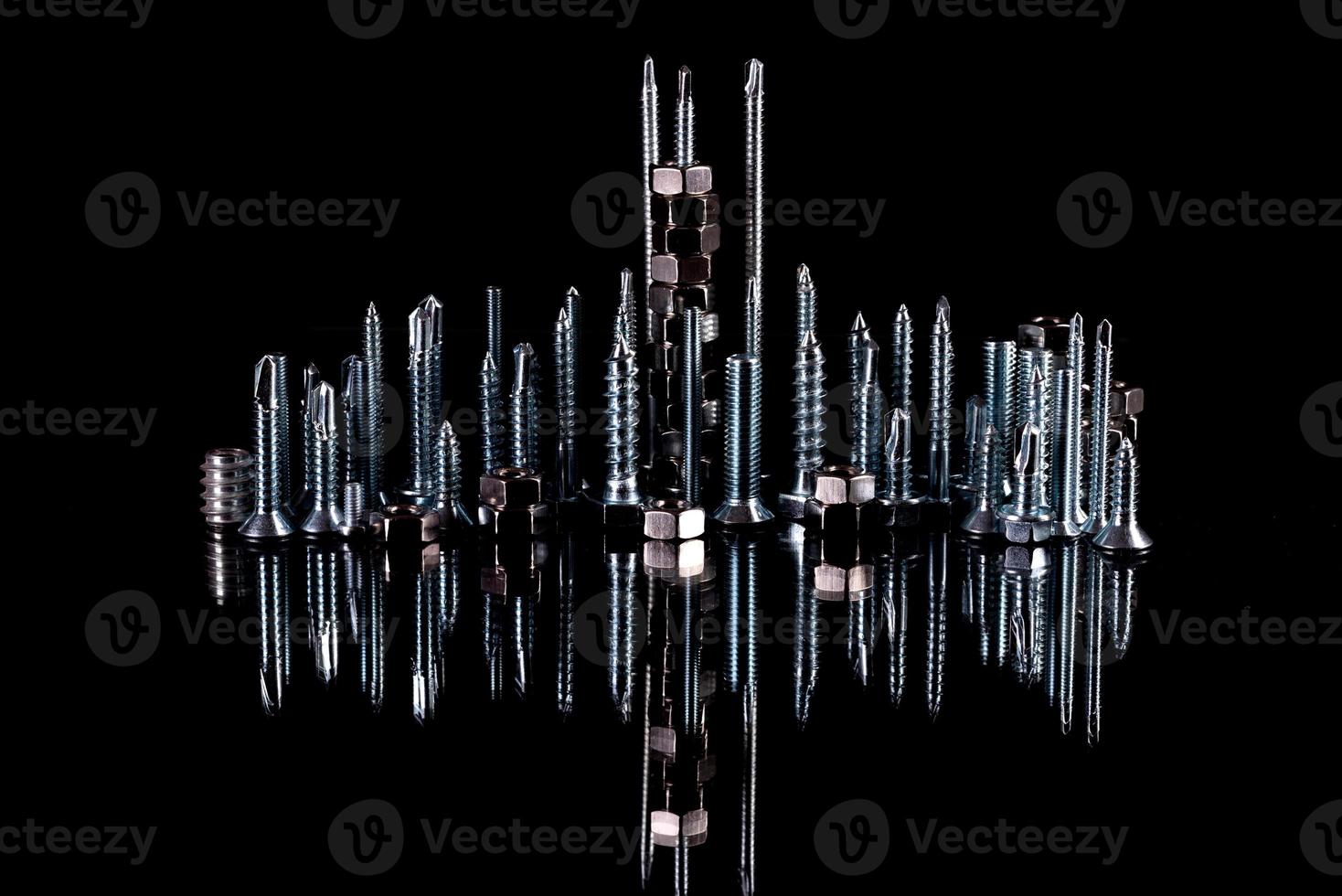 A fantastic city made of bolts, nuts, screws and self-cuts on a black background with reflection photo