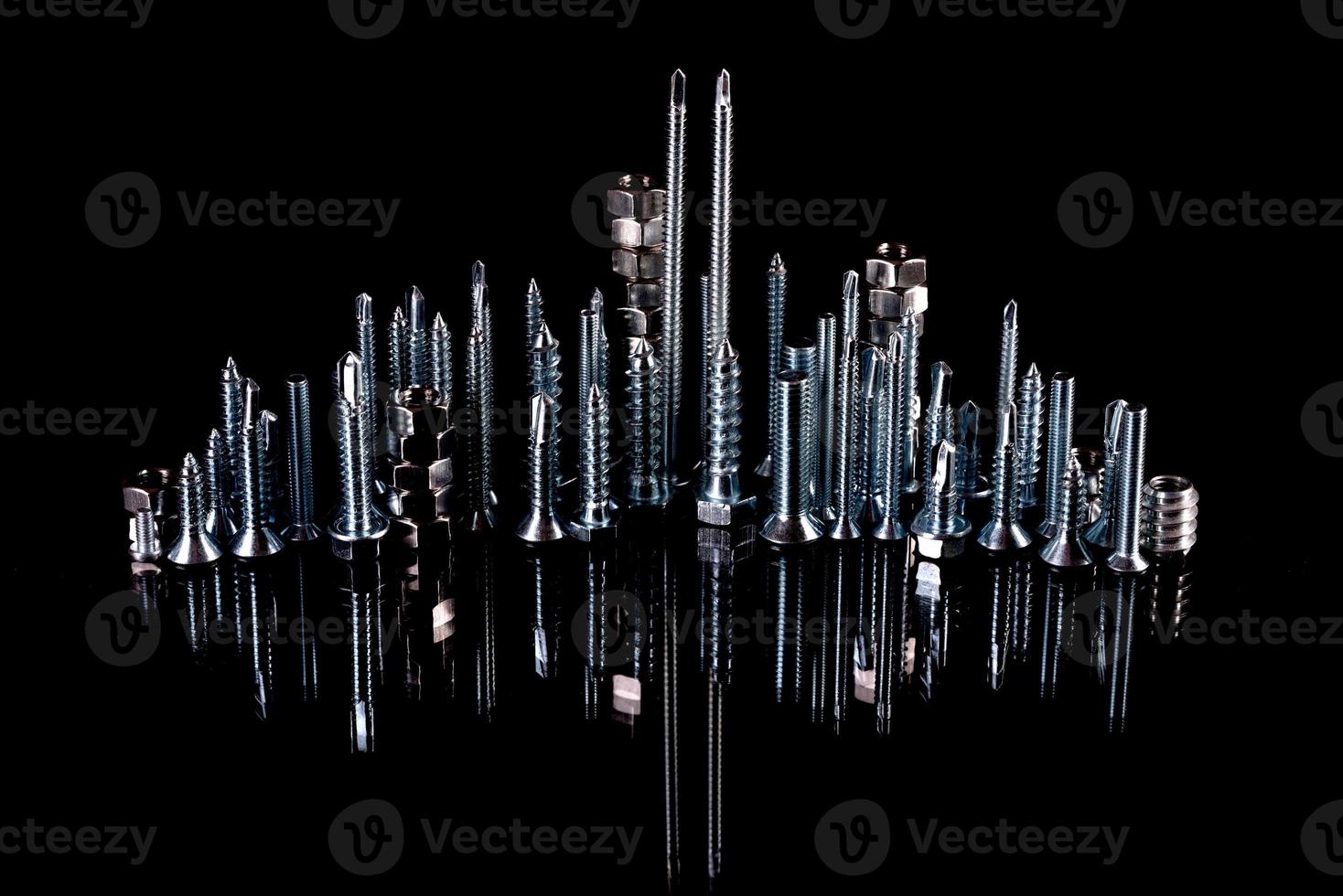 A fantastic city made of bolts, nuts, screws and self-cuts on a black background with reflection photo