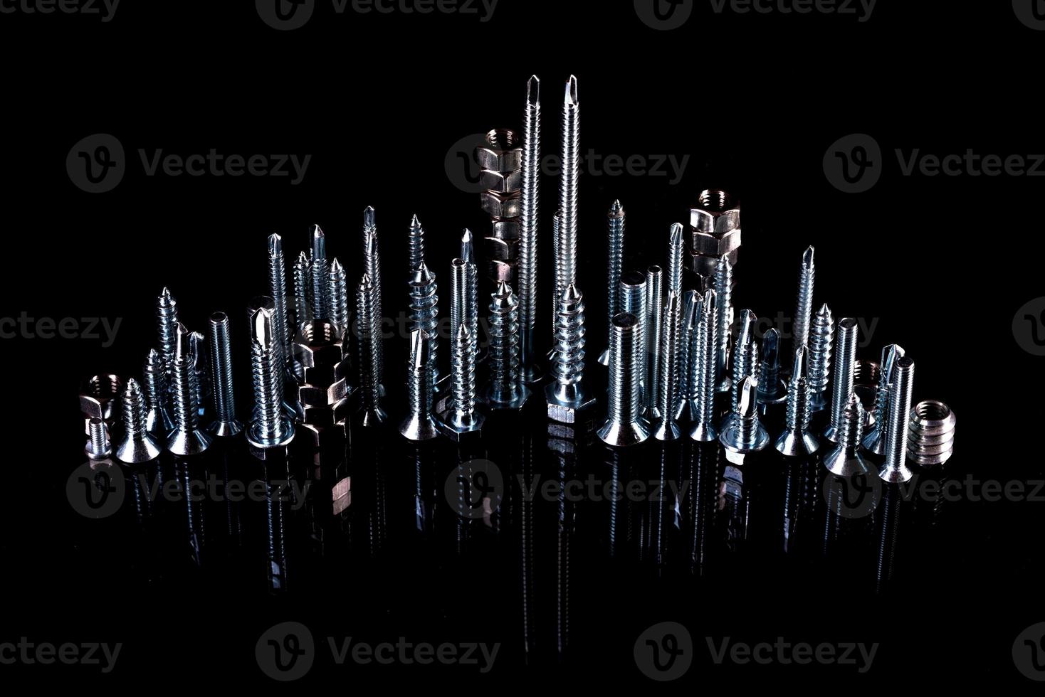 A fantastic city made of bolts, nuts, screws and self-cuts on a black background with reflection photo