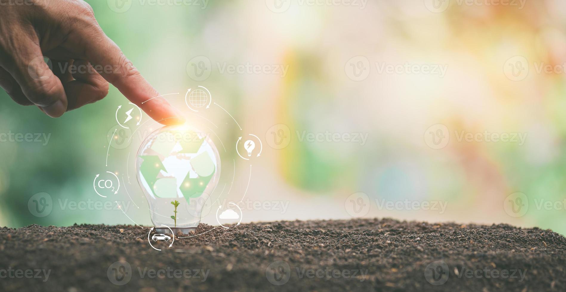A man's fingers are placed on a light bulb in the ground, photo