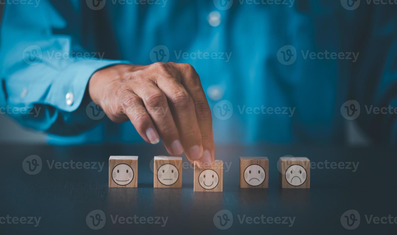 Man's hand holding a wooden block lying on the table indicates selection photo