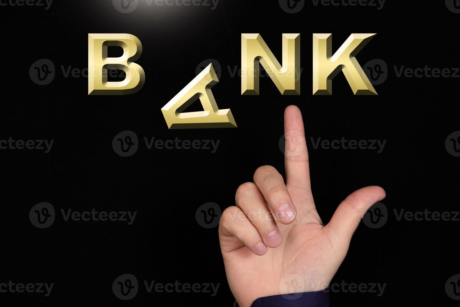 A finger points to the word Bank, made of miniature three-dimensional letters, with the letter A falling, on a black background. photo