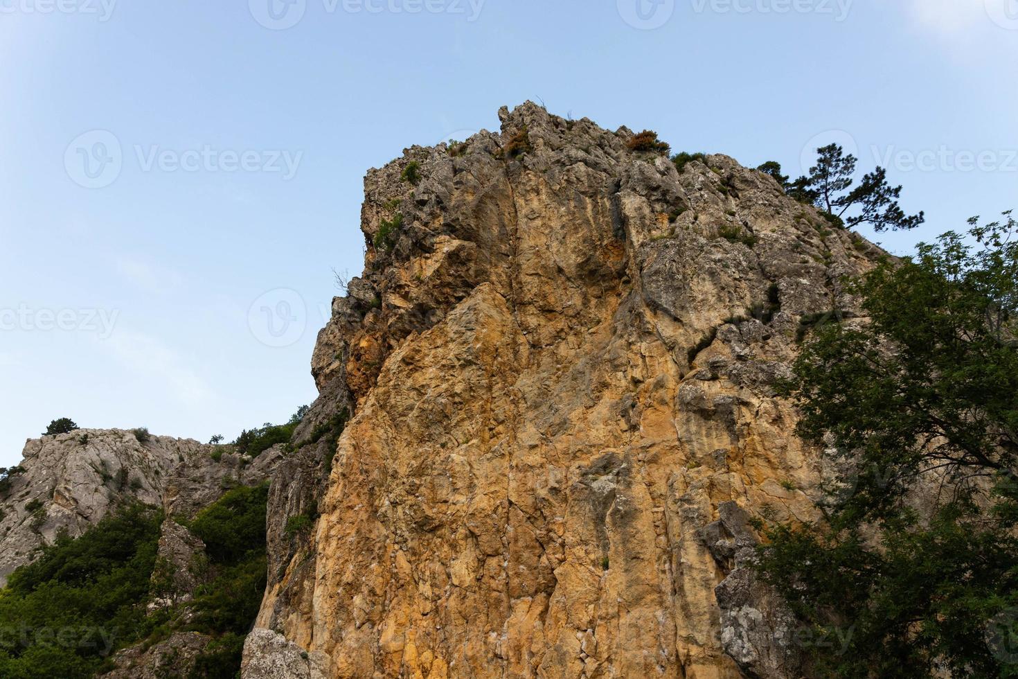 Large wild red limestone cliffs with sparse vegetation. photo