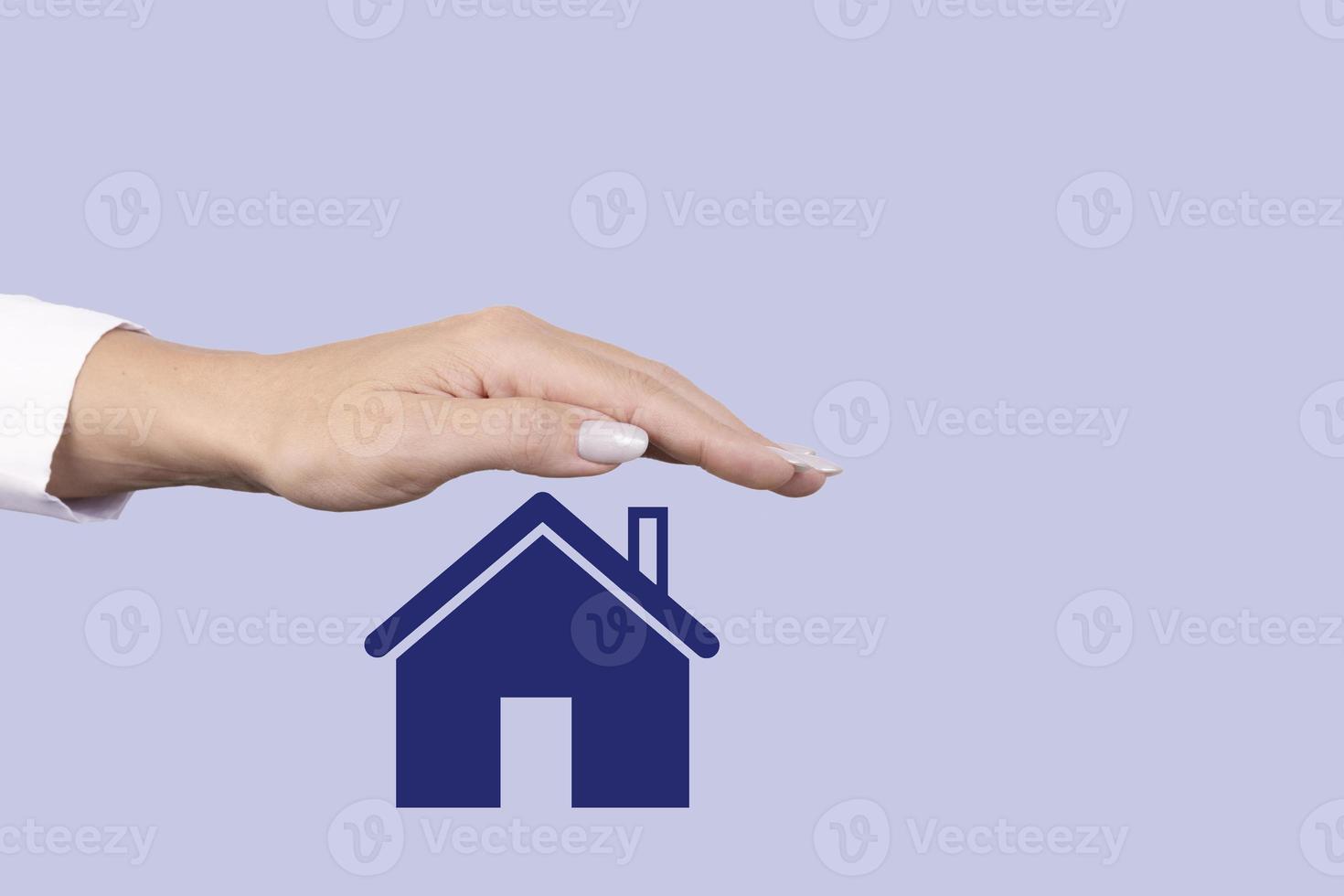 Real estate sale, rental, insurance and protection concept. A female hand covers the icon with a house. Copy space. photo
