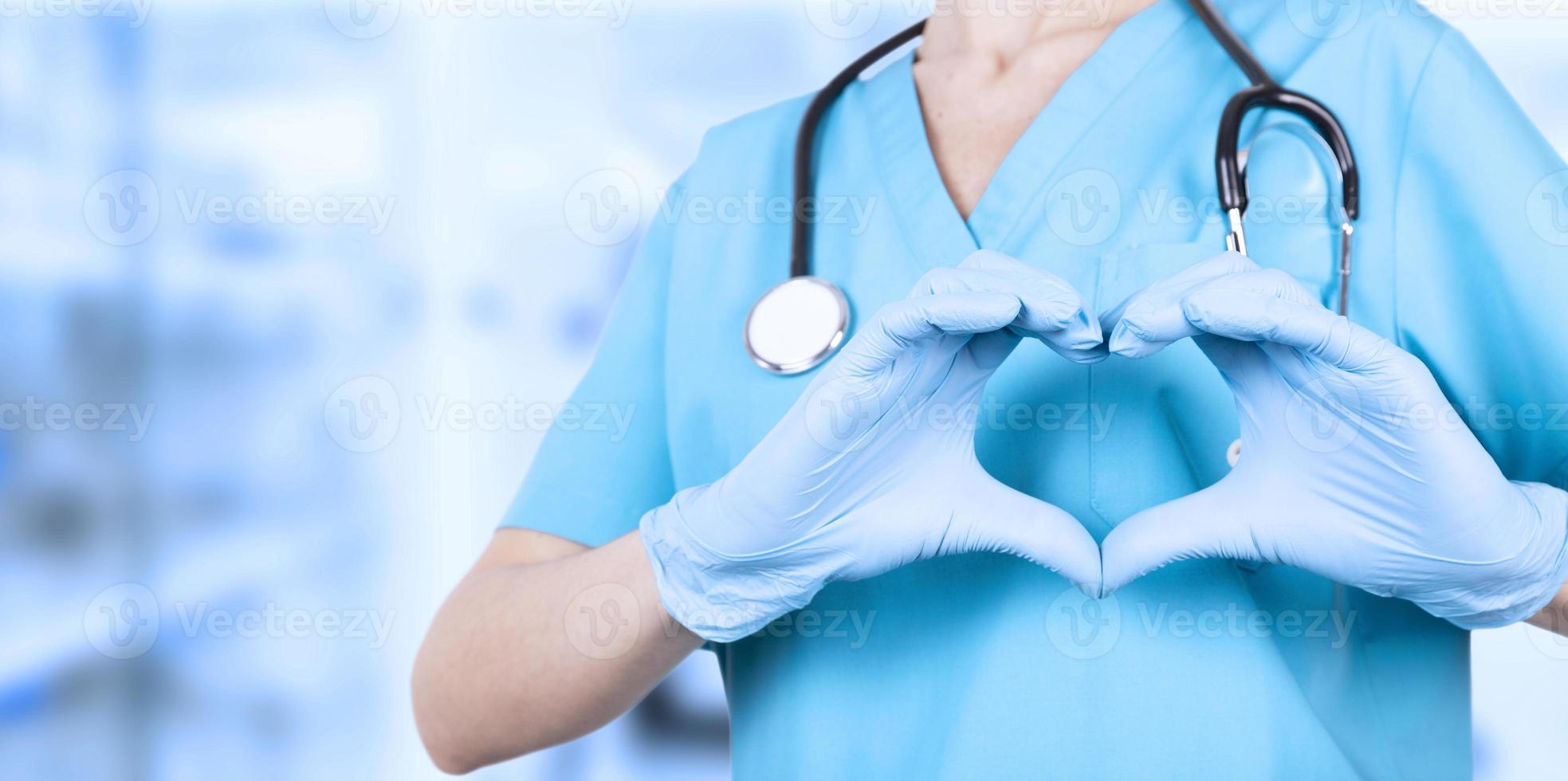 mujer doctora, manos en guantes azules médicos, formando un corazón. te amamos. copie el espacio foto